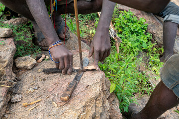 Hunters from Hadzabe tribe in Tanzania. Making a fire with wood stick friction.