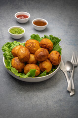 bread rolls stuffed with potatoes placed on a lettuce leaf served with green and red sauces