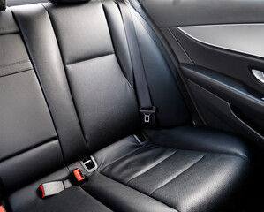 Back passenger black leather seats in modern luxury car. Black perforated leather with stitching. Car inside. Leather comfortable red seats. Car interior details