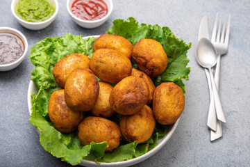 bread rolls stuffed with potatoes placed on a lettuce leaf served with green and red sauces