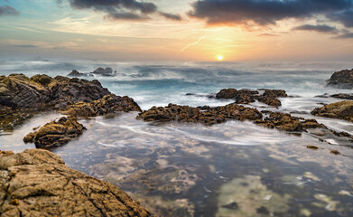 Beautiful seascape, ocean views, rocky coastline, sunlight on the horizon. Composition of nature. Sunset scenery background. Cloudy sky. Reflection of water. California coast. Shot with a long