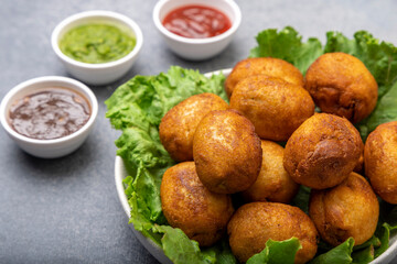 bread rolls stuffed with potatoes placed on a lettuce leaf served with green and red sauces