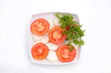 the red tomato with radish sliced and green coriander in the plastic plate isolated on white background.