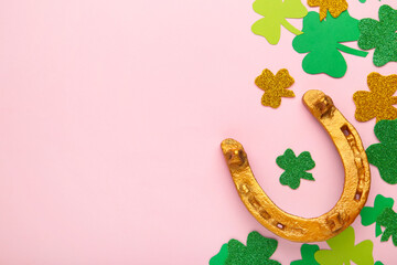 Green clovers and gold horseshoe on pink background for St. Patrick's Day Holiday.