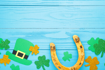 Green clovers and gold horseshoe on blue wooden background for St. Patrick's Day Holiday.
