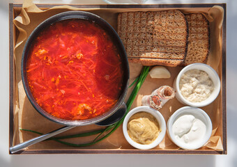 Russian or Ukrainian national soup, borscht with lard, horseradish and sour cream on a wooden tray in a cafe or restaurant. top view