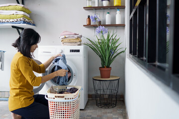 woman in front of the washing machine doing some laundry loading clothes inside