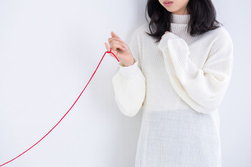 白い服を着た女性が赤い糸を指につけている　運命　恋愛　出会い love