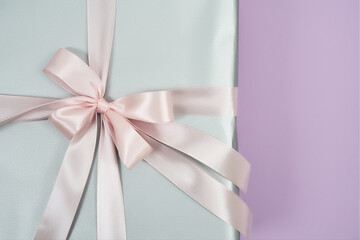 International Womens Day. Close up shot of a silver gift box with pink bow and ribbon on a purple background