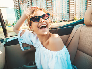 Portrait of young beautiful and smiling hipster female in convertible car. Sexy carefree woman...
