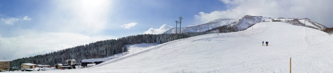 Fototapeta na wymiar Panorama view of a ski resort with few people on a sunny day (Niseko, Hokkaido, Japan)