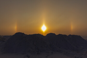 Sunny optical halo effect in the early morning on the background of snow hummocks. The concept of...