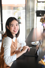 Portrait of young asian woman sitting in cafe with computer tablet and smiling to camera.