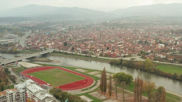 Athletic Field At The Embankment Of Ibar River In Kraljevo, Serbia With Traffic At European Route E761. aerial drone (orbit)