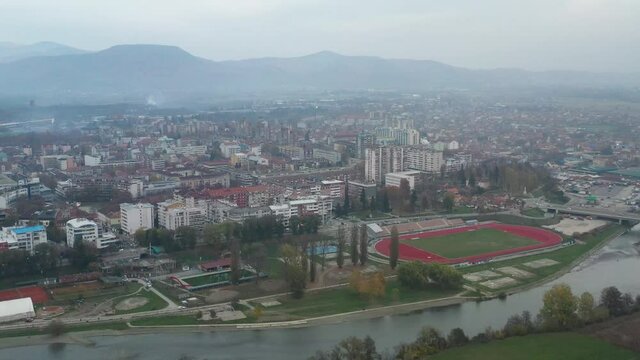 Buildings And Athletic Field On Vast Landscape In Kraljevo, Serbia On A Foggy Day. aerial drone, arc shot