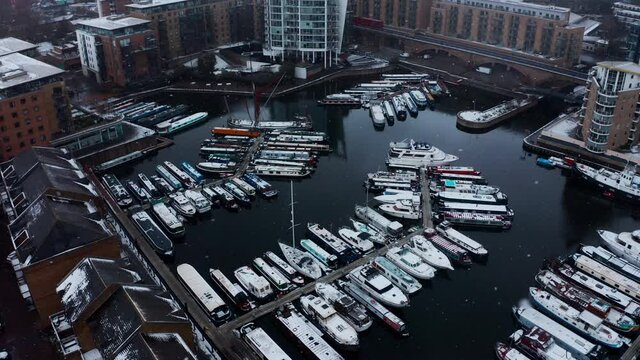 Drone shot over Limehouse waterside and marina boats in the snow London