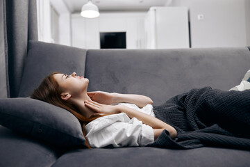 woman at home lying on the couch covered with a blanket health problems