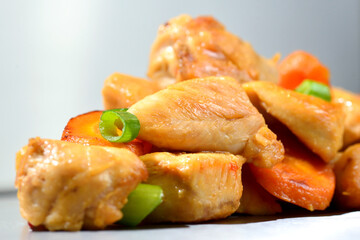 Roasted chicken seasoned slices with carrots and leeks on a stainless steel background