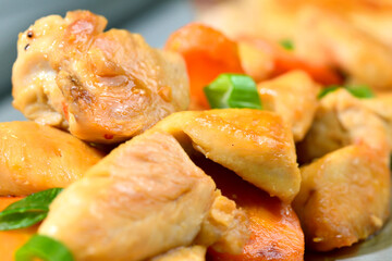 Roasted chicken seasoned slices with carrots and leeks on a stainless steel background