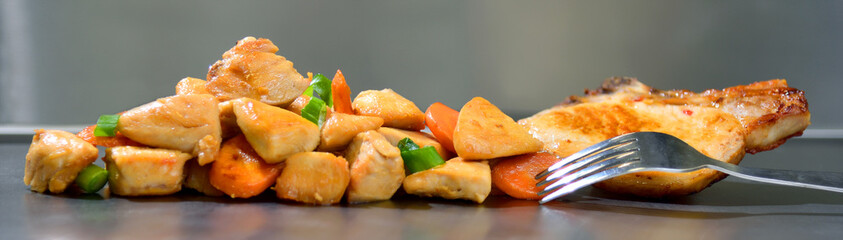 Roasted chicken seasoned slices with carrots and leeks on a stainless steel background