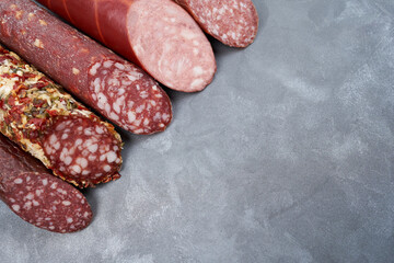 Assortment of raw smoked sausages on a gray table with copy space.