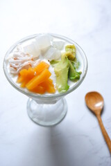 a glass of es teler or various fruits with coconut milk soup and ice cubes