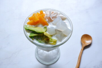 a glass of es teler or various fruits with coconut milk soup and ice cubes