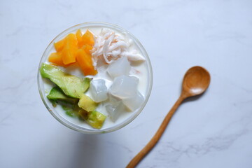 a glass of es teler or various fruits with coconut milk soup and ice cubes