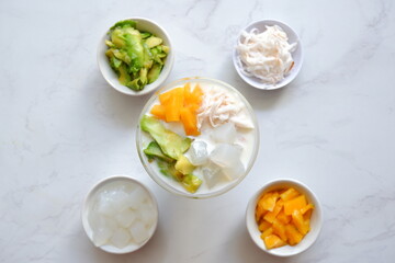 a glass of es teler or various fruits with coconut milk soup and ice cubes