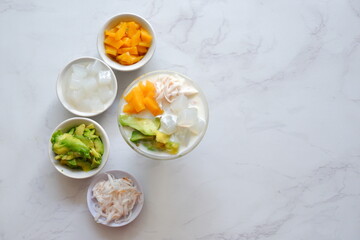 a glass of es teler or various fruits with coconut milk soup and ice cubes