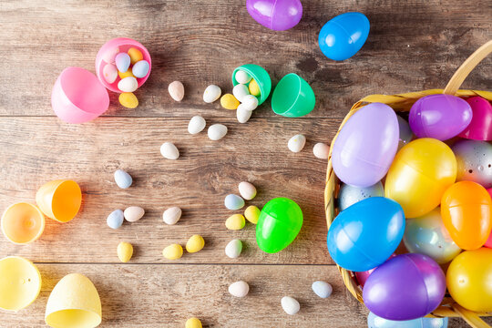 Flat lay image of plastic easter eggs being filled with chocolates before easter egg hunt. It is a fun activity for children who search for eggs and get the chocolates.