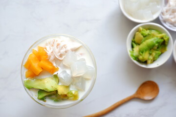 a glass of es teler or various fruits with coconut milk soup and ice cubes