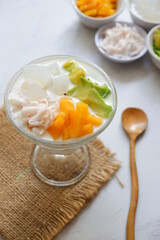 a glass of es teler or various fruits with coconut milk soup and ice cubes