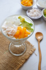 a glass of es teler or various fruits with coconut milk soup and ice cubes