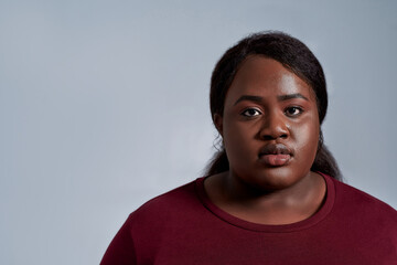Close up portrait of calm plus size young african american woman in casual clothes looking at camera