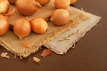 Onions close-up on the kitchen table. Vegetables in the form of onions on sacking. Lots of onions on a cutting board.