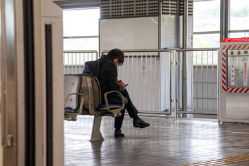 駅のホームのベンチに座る人