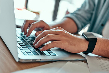 Closeup businessman hands typing on laptop keyboard in cafe.