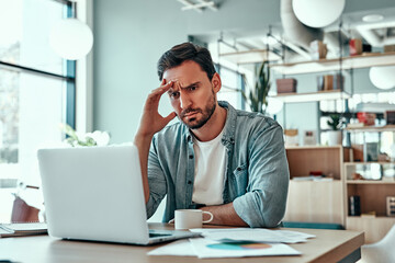 Thoughtful businessman looking at laptop screen