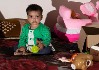 Asian Indian baby girl portrait closeup playing with toys. A cute baby girl .