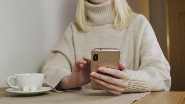 Young woman in cafe works with a smartphone. woman chatting, drinking coffee and relaxing. close-up.