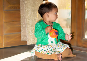 Asian Indian baby girl portrait closeup playing with toys. A cute baby girl .