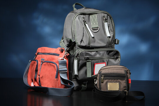 Bags Of Different Types And Sizes Stand Side By Side. Urban Backpack Next To Small Bags. Three Bags Are On Table. Concept - Shop Of Handbag And Backpacks. Sale Of Modern Urban Backpacks.