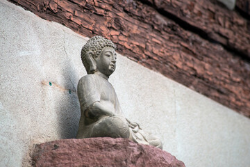 Closeup of stoned little buddha on  building facade of house in the street