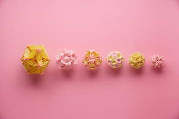 Set of multicolor handmade modular origami balls or Kusudama Isolated on pink background. Visual art, geometry, art of paper folding, paper crafts. Top view, close up, selective focus, copy space.
