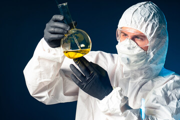 Virologist in a protective suit. There's a dangerous liquid in his test tube. Test tube with a virus in hands of a virologist. Employee of virology laboratory. Dealing with dangerous viruses