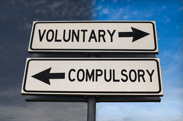 Voluntary versus compulsory road sign with two arrows on blue and grey sky background. White two street sign with arrows on metal pole. Two way road sign with text.