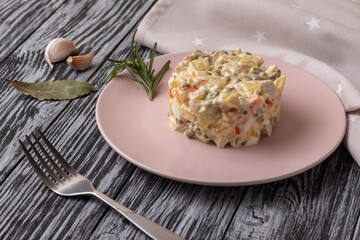 Traditional russian Olivier salad with meat and vegetables. On a black wooden table.