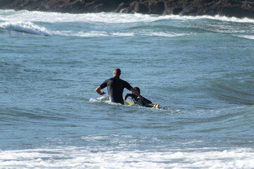 View of father teaching kid to surf