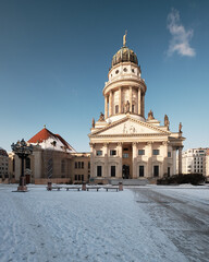 Fototapeta na wymiar Gendarmenmarkt historic square in Berlin with French Cathedral. Picture taken n a bright Winter day with blue sky and snow.